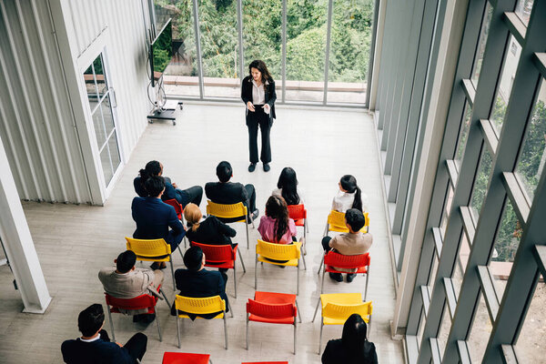 Birds-eye view of a productive executive meeting. Businesswoman and businessman engage in discussions. Teamwork, planning, and strategy lead to corporate success in a diverse office