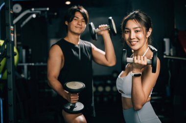 Güçlü ve seksi bir adam, bir ağırlık dambılı tutuyor ve mesafeye bakıyor, kaslı pazılarını ve atletik vücudunu bir fitness portresi için gösteriyor. Yaşam tarzı fitness konsepti