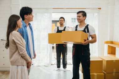 Bir çift, kamyondan kutuları boşaltan nakliyecilerden yardım alıyor. Profesyonel hizmet, taşınma sırasında müşteri memnuniyetini sağlar. Etkili takım çalışması gösterildi. Yeni ev taşınıyor