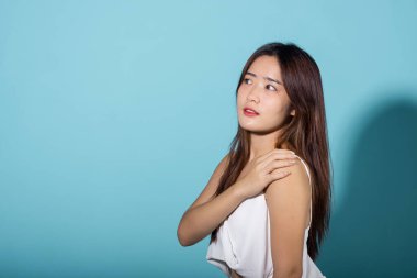 Kolunu ve elini kaldıran ve güneş ışığını engelleyen bir portre, genç kadın yüzünü örten bir örtü, mavi arka planda izole edilmiş güneş ışığı ve ultraviyole ışıklarını koruyan bir stüdyo, kozmetik güneş kremi reklamı