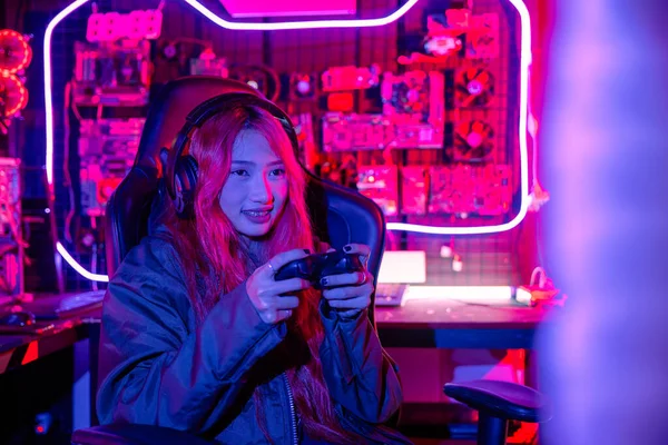 女人戴着游戏耳机玩电玩电玩游戏 游戏者用控制杆控制比赛 用电脑霓虹灯玩网络游戏 — 图库照片