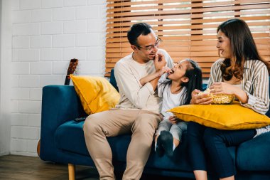 Keyifli bir aile, televizyon ve patlamış mısırdan keyif alır. Birlikte ve kaynaşarak geçen anları teşvik eder. Baba, anne, kız ve kardeş kahkahalar paylaşıyor. Gerçek aile mutluluğunun simgesi..