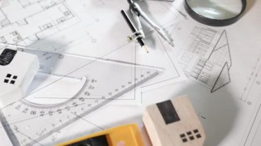 Mimari proje işyeri. Mimarlık bürosundaki masa başında tamir aletleri olan ev planı tasarım kağıtlarının üst görünümü, Mühendislik mimari tasarım araçları konsepti