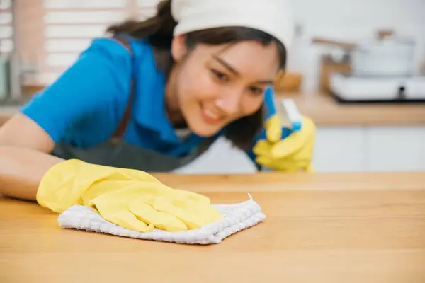 液体のスプレーおよびラグが付いている集中されたアジアの女性のクリーニング サービスの専門のワイプの台所カウンター ハウスキーピングは家庭の衛生と清潔さを確保します ホームケアをきれいに消毒する メイド — ストック写真