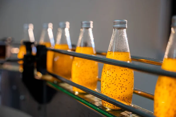 飲料工場は 自動化されたボトリングラインを効率的に有機バジルまたはチアシードドリンクと混合された透明なボトルを満たします 質の生産および清潔は明白です — ストック写真