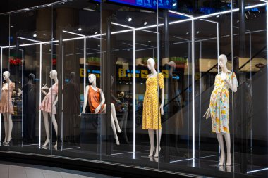 Moda endüstrisi için çeşitli pozlar ve stiller sunan vitrin vitrininde renkli ve sanatsal mankenlerle dolu bir vitrin.