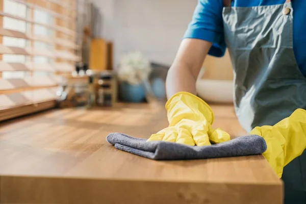 保護グローブのメイドは居心地の良いキッチンで木製のテーブルを拭きます 完全な家の整頓のための専門のクリーニングプロダクトを使用して クリーナー作業安全手袋衛生ルーチン メイドハウスキーピングのコンセプト — ストック写真