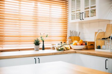 Bu İskandinav iç mekanında, gri döşemeleri ve ahşap mobilyaları olan modern bir mutfak göze çarpıyor. Büyük bir pencere ve bir bitki bu rahat, temiz beyaz evin lüksüne katkı sağlar..