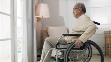 Yalnız, yaşlı, düşünceli, üzgün yaşlı bir adam huzurevinde yatak odasının pencerelerine bakıyor. Asyalı, yaşlı bir adam sakat.