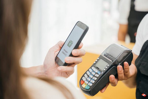 После завершения движения пара платит через QR-код смартфона. Рабочий носит коробку. Профессиональные грузчики обеспечивают успешное переселение. Показаны бизнес и промышленность. Онлайн-оплата переезда