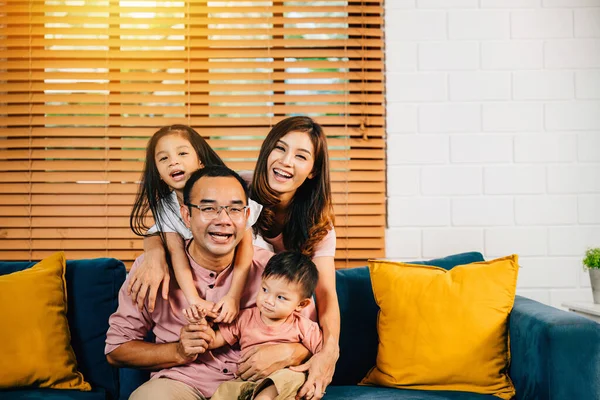 A cheerful family in their comfortable modern house shares a sweet moment on the sofa. Parents daughters and siblings bond laugh and embrace radiating joy and togetherness.