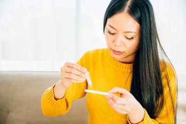 Bir kadın evinde COVID-19 testi için hızlı bir antijen test kiti kullanıyor ve burnuna çubuk sokuyor. Virüs önleme ve pandemik koruma tedbirleri.