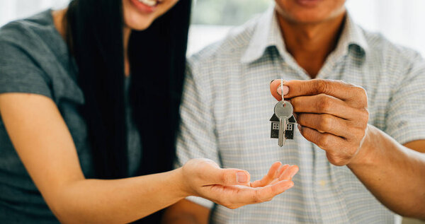 A cheerful couple celebrates homeownership holding keys to their new house. Reflecting happiness success and the thrill of a significant investment in real estate.