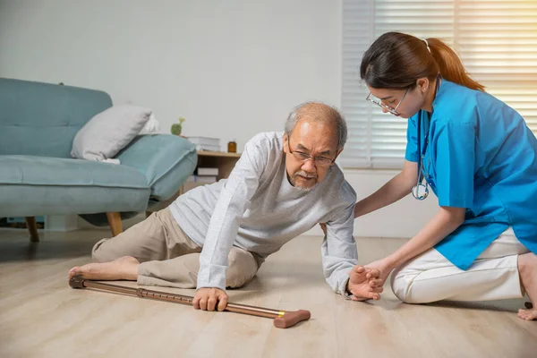 Disabled elderly old man patient with walking stick fall on floor and caring young assistant at nursing home, Asian older senior man falling down on lying floor and woman nurse came to help support