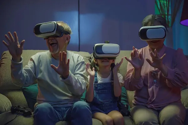 Asian elderly with child play VR video game, family entertainment, granddaughter and grandparents playing together exciting interesting video games using virtual reality headsets living room at home