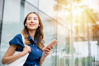 Sanal sohbet ve sosyal medya için kablosuz kulaklık ve akıllı telefon kullanan mutlu genç bir kadın. Bu portre modern bir yaşam tarzını gösteriyor..