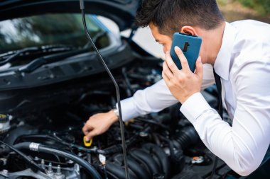 Asyalı işadamı yolda bir araç kazası geçirdikten sonra araba sigortasını arıyor. Beyaz gömlek giyiyor. Cep telefonu ve baş parmağı yukarıda. Yol kenarında şifrelenmiş ve yardım bekliyor..