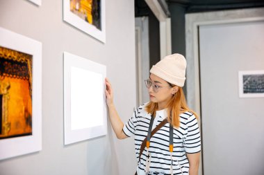 Fotoğraf çerçevesinde fotoğraf ziyaretinden sergi sergisi sanat galerisine doğru eğilmeye, Asyalı kadın resim galerisi koleksiyonuna kamera tutmaya, duvardaki çerçeveli resimlere ve