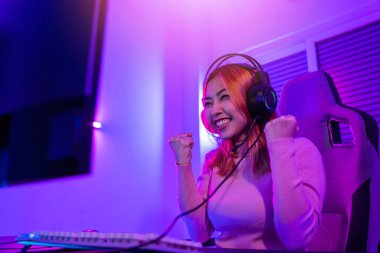 Kazanmak. Happy Gamer 'ın genç oyuncuları çevrimiçi bilgisayar oyunu oynuyorlar. Turnuvayı kazanmak için ellerini kaldırıyor. Oyun kulaklıkları takan genç bir kadın internette video oyunu oynuyor.