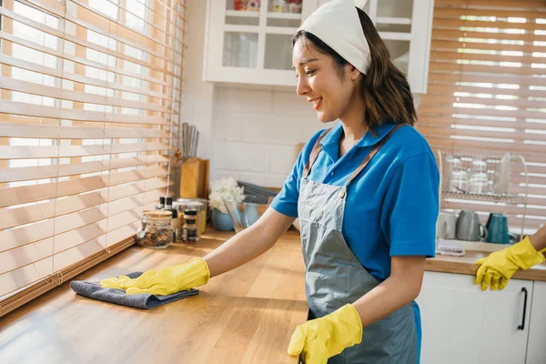 現代の台所の主婦かメイドは食卓の表面を拭きます 家庭の整頓のための専門のクリーニングプロダクトを使用して 作業安全グローブ衛生ルーチンでクリーナー メイドハウスキーピングのコンセプト — ストック写真