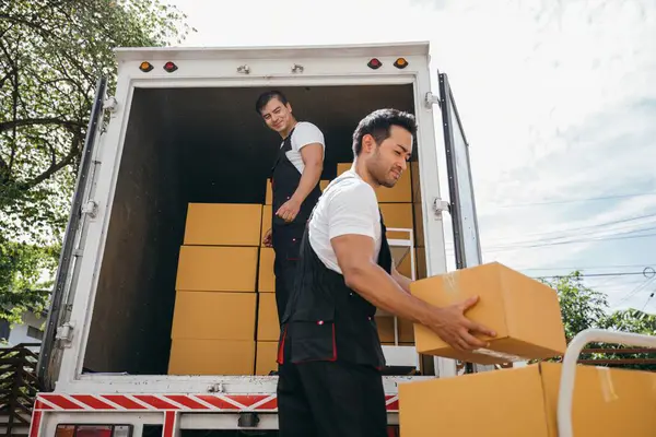 Workers unload boxes outdoors. Moving service teamwork as delivery men carry boxes. Cooperation in relocation service. Smiling employees working together. relocation cooperation Moving Day