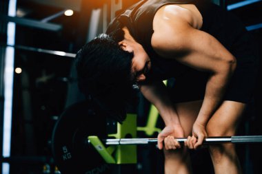 Spor salonunda dayanıklılık ve ağırlık kaldırma egzersizi için güçlü vücut halterleri olan fit ve seksi bir adam. Güç kaldırma eğitim kavramı