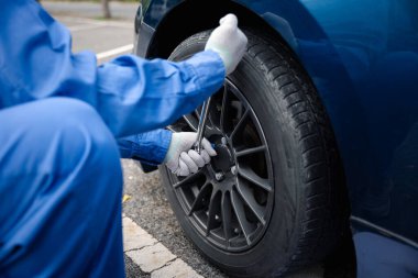 Araba direksiyonu tutan olgun bir adam, onu değiştirmeye hazırlanıyor. Otomobil tamirhanesinde çekilmiş..