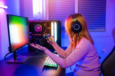 Kaybediyorum. Oyun oynayan oyuncu, akıllı telefonuyla neon ışıkları olan bir bilgisayar oyununda başarısız oldu. Oyun bitti. Kafası karışmış, kulaklık takan Asyalı kadın cep telefonu çalıyor.