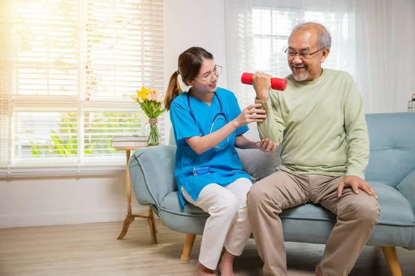 亚洲护士理疗师帮助老年人在养老院提起哑铃 年轻护士提供护理支持 利用哑铃锻炼训练老年人坐在沙发上 医疗保健医疗 — 图库照片
