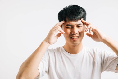 Acı veren bir baş ağrısı ve stresten bunalmış Asyalı bir adam üzgün bir ifadeyle başını tutar. Stüdyo çekimi, rahatsızlığını ve hastalığını vurguluyor..