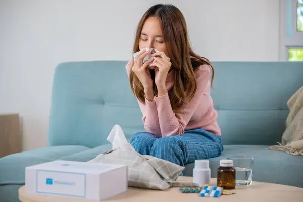 Sick woman. Beautiful female health problem blowing nose use pharmacy kit box delivery service from hospital, delivery pharmacy concept, Asian young girl cold sick she sneeze with tissue paper on sofa