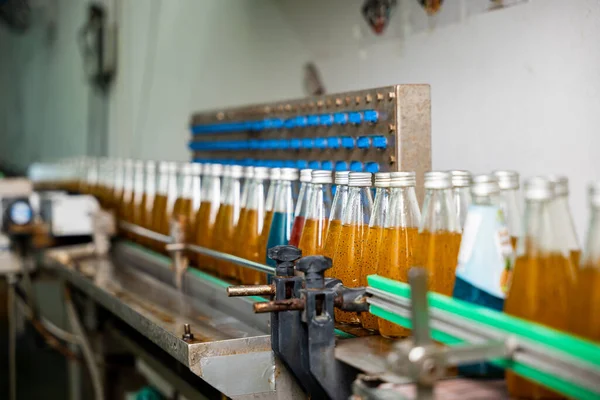 透明ボトルは 飲料工場のコンベヤベルトに沿って移動し ザクロと混合された有機バジル種子ドリンクで満たされます このきれいな自動化された製造は品質を保証します — ストック写真