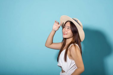 Korumada el ve kol kaldıran ve stüdyoda gün ışığını engelleyen bir kadın mavi arka planda izole edilmiş, Asyalı genç kadın gülümsüyor. Kapak yüzü, güneş ışığı ve ultraviyole ışınlarını koruyor, güneş kremi reklamı yapıyor.