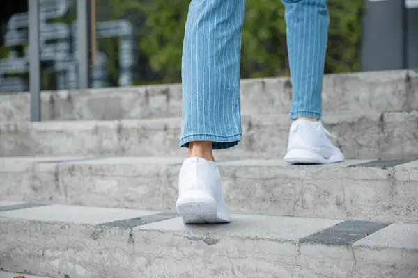 A businesswoman in sneakers conquers the city stairs, symbolizing her determined path. Each step reflects her unwavering progress towards success, highlighting her professional growth. step up