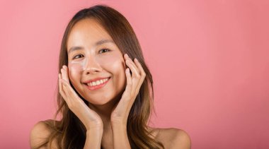 Kadınlık. Asyalı güzel, genç bir kadın gülümseyen kozmetik bantlar gözlerinin altına jel, portre kadın temiz cilde dokunuyor yüzüne tıbbi hidrojel göz bandı, pembe arka planda izole edilmiş, cilt bakımı.