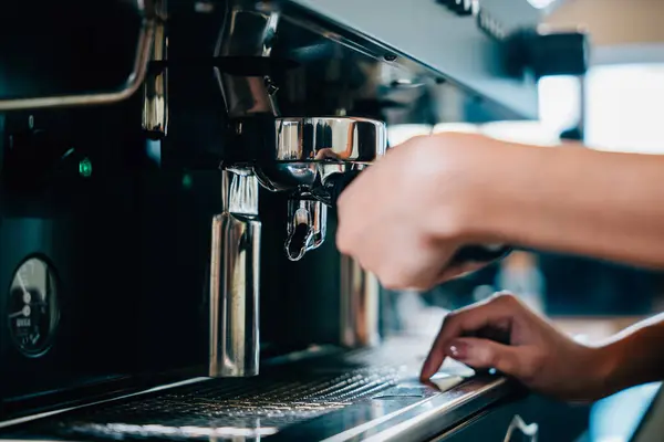 Fresh tasty coffee brewed by coffee machine at restaurant or pub. Step by step guide to professional coffee making. Close up of machine hand holding handle pouring drink.