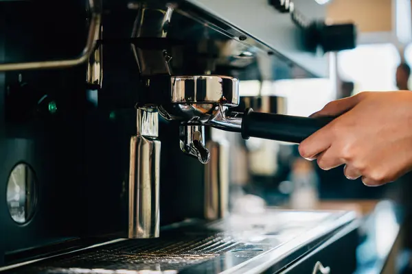 At restaurant or pub coffee machine brews fresh tasty coffee. Step by step guide to professional coffee making process. Close up of machine hand holding handle pouring espresso.