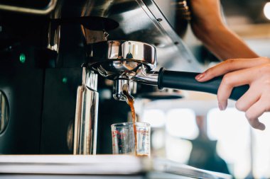 Kahve dükkanında espresso makinesi kahve yapar. Kadehlere espresso dökmek kafedeki modern teknolojiyi ortaya çıkarıyor. Akıcı sıvı buhar, şeffaf cam bardaklar..