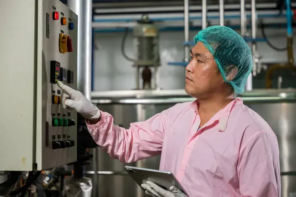 Worker employs tablet in beverage production while an engineer supervises soda water filling. Emphasizing quality control ensures top industry standards for bottle manufacturing.