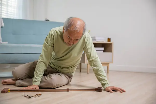 Asian elderly man retired headache after fall down, Sick senior old man falling down lying on floor at house alone with wooden cane walking stick in living room, Health care and medicine concept