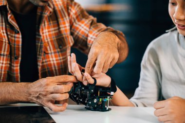 Öğretmen, öğrencilerin sınıf tasarımı ve teknoloji dersinde robotik kol yapmalarına yardım ediyor. Yenilikçi keşifleri teşvik etmek ve bilim eğitimi için kodlama becerileri. Robot el. Yenilik ve teknoloji kavramı