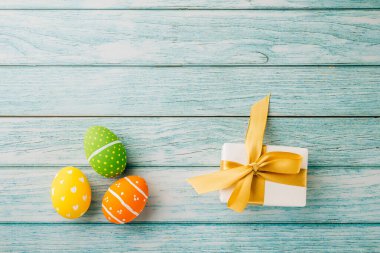 Mutlu Paskalya Günü Kavramı. Üst görünüm tatil afişi arkaplan tasarımı. Paskalya yumurtaları ve mavi ahşap arka planda hediye kutusu.