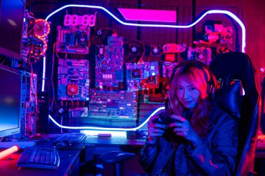 Sanal turnuva için joystick kumandası kullanan oyuncu çevrimiçi bilgisayar ışıklarıyla video oyunu oynuyor, kadın evde canlı yayın esport konsolu oynarken oyun kulaklığı takıyor