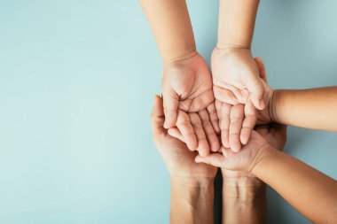 Soyutlanmış arka planda aile üst görünümü elleri var. Ebeveynler ve çocuklar, Aile ve Veliler Günü için destek ve sevgi ifade eden boş bir alan tutuyorlar..