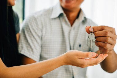 Gülümseyen bir çift, yeni evlerinin anahtarlarını gösteriyor. Mutluluğu ve ev sahipliğindeki başarıyı simgeliyor. Neşe başarısını ve önemli bir yatırımın heyecanını yansıtıyor..