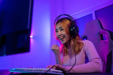 Kazanmak. Happy Gamer 'ın genç oyuncuları çevrimiçi bilgisayar oyunu oynuyorlar. Turnuvayı kazanmak için ellerini kaldırıyor. Oyun kulaklıkları takan genç bir kadın internette video oyunu oynuyor.