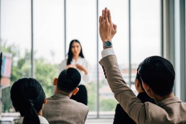 Bir konferanstaki seminer sınıfında, büyük bir grup katılım için el kaldırıyor. İşbirlikçi eğitimi sembolize ederek, ilgili izleyiciler cevapları elinde tutuyor..