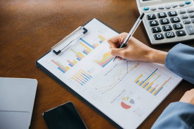 Kâğıt grafiklere pazarlama notu yazan iş kadını, iş finans ve muhasebe kavramı, kafede çalışan genç kadın serbest mali işler verileri.