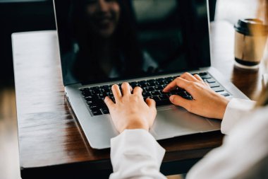 Dizüstü bilgisayarda klavye yazan, ofis dışında online çalışan Asyalı genç iş kadını yaşam tarzı kafeteryada dizüstü bilgisayar kullanan mutlu bir serbest yazar.