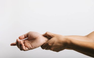 Bilek ağrısına dayanan, muhtemelen karpal tünel sendromundan dolayı üzgün görünen bir adamın portresi. Stüdyo çekimi beyaz arka planda izole edilmiş, sağlık hizmetlerini ve tıbbi konsepti gösteriyor.